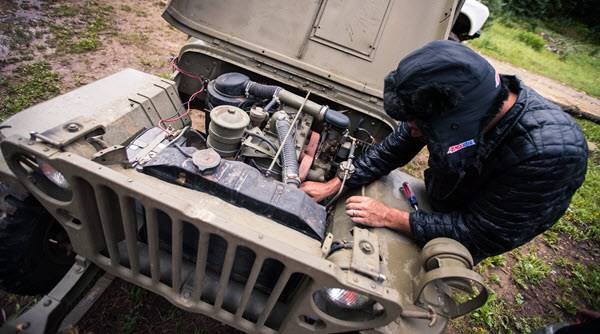 A person Working on a Jeep Engine using AMSOIL Synthetic Motor Oils.