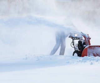 man with a snow blowing machine working in winter day